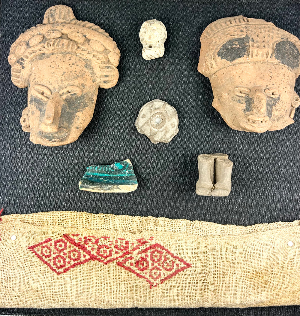 Framed Pre-Columbian collection with masks, ornaments, figurines, and textile, white background