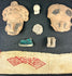 Framed Pre-Columbian collection with masks, ornaments, figurines, and textile, white background