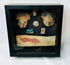 Ancient Mesoamerican artifact display, terracotta and textile pieces mounted in black frame