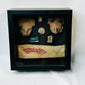 Framed display of ancient terracotta masks, carved ornaments, and Pre-Columbian woven textile