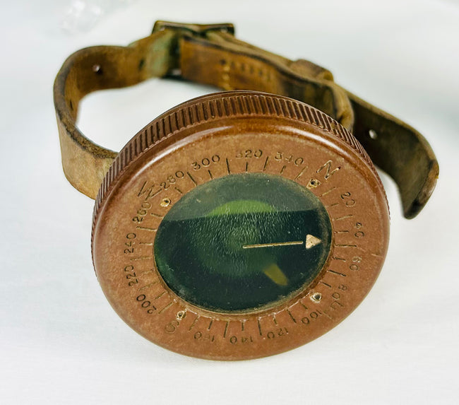 World War I soldier’s compass, spent shell casing, and sepia troop photograph, displayed on white