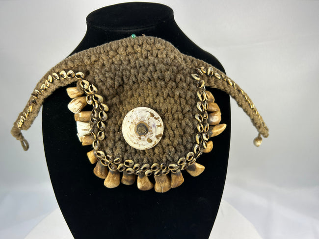 Melanesian ritual adornment featuring cowrie shell and pierced animal teeth