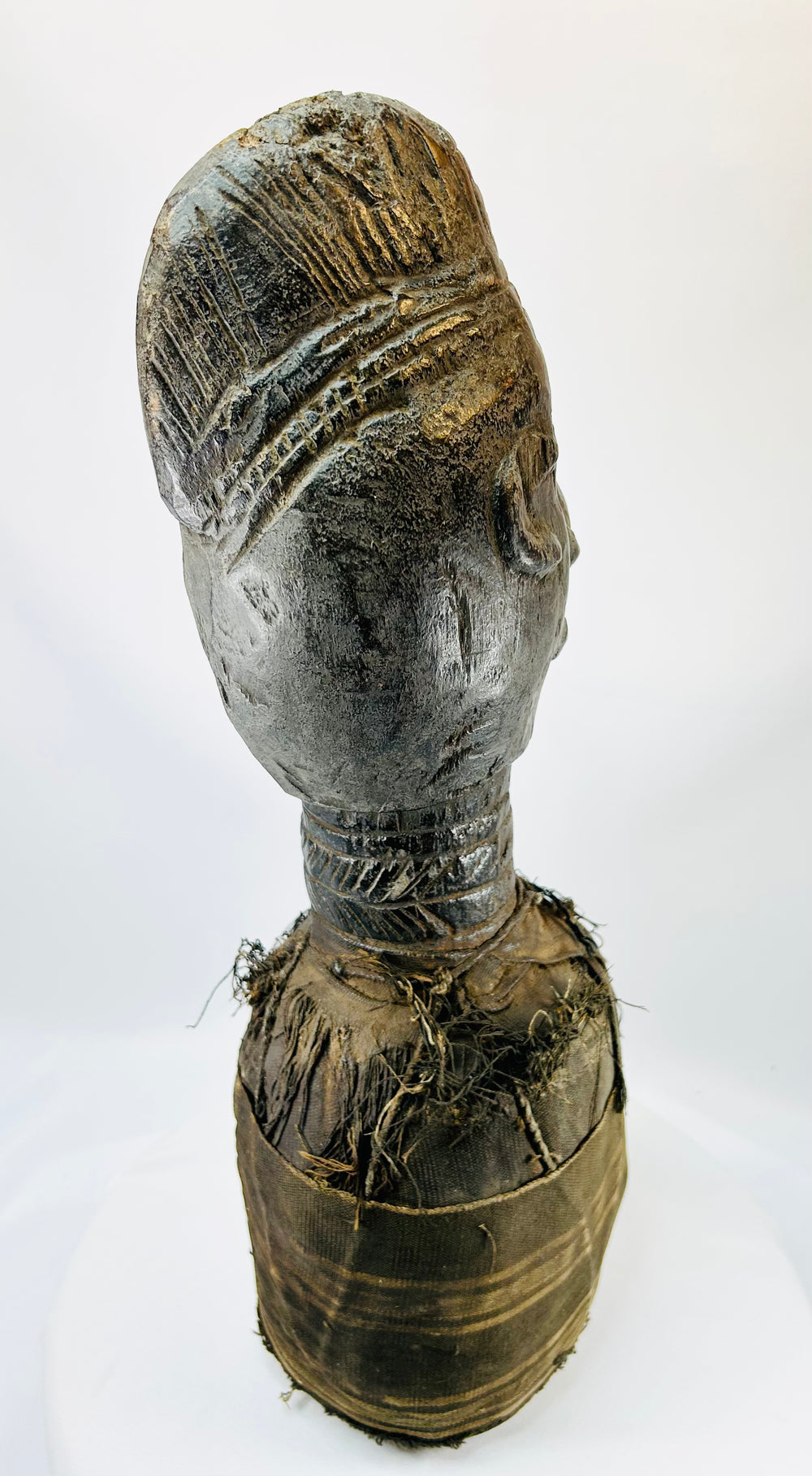 Wooden sculpture from West Africa featuring elongated facial features and natural fiber torso wrap