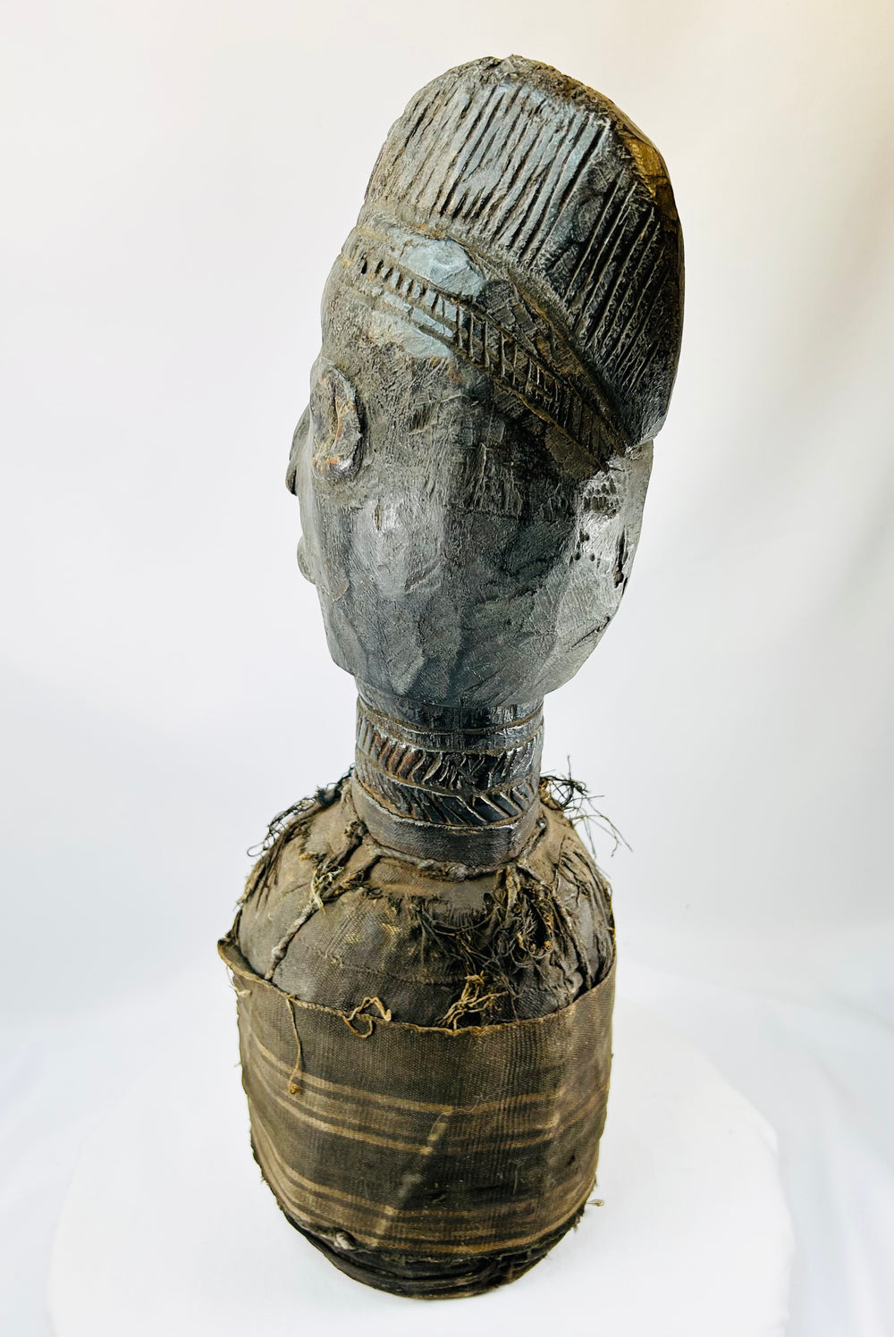 Central or West African carved wooden figure with elongated face and preserved decorative fibers