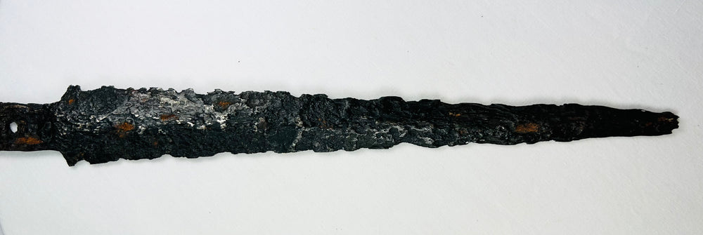 Close-up of 14th-century European dagger blade with heavy corrosion and pitted surface, displayed flat on a white background.