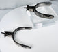 Decorated steel cowboy spurs with silver overlays, strap slots, and aged surface