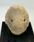 Early Pre-Columbian terracotta head fragment with rounded facial features and drilled eyes, West Mexico, displayed on black stand, 300 BCE–300 CE
