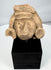 Ancient Mexican stone head with large ear ornaments and stylized facial features