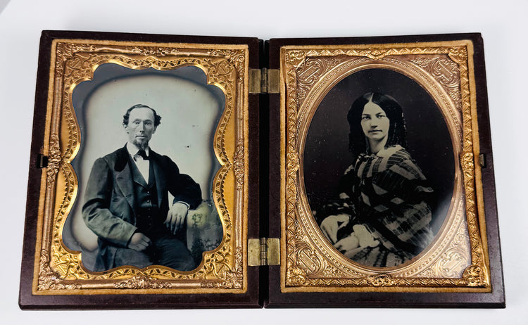 Rotating view of a mid-19th-century double ambrotype set with portraits of a Victorian gentleman and young woman, gilt brass mats, velvet lining, and an ornate molded thermoplastic union case