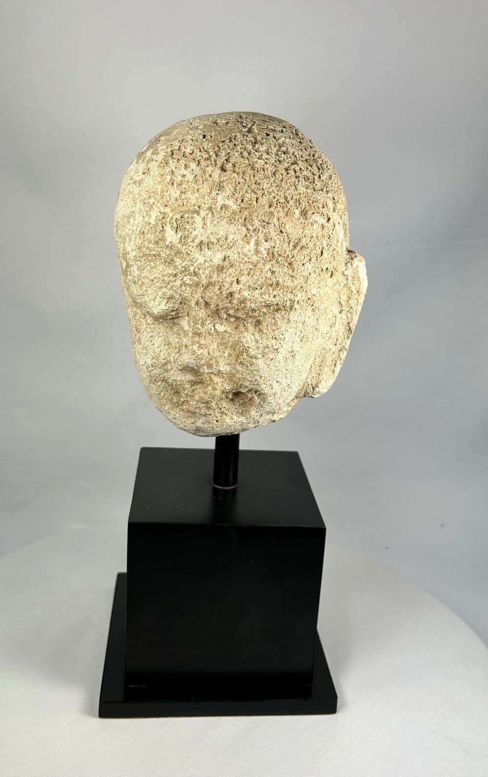 Detailed macro image of Southeast Asian stone Buddha sculpture, 13th–14th century head fragment with meditative features and soft carving lines.