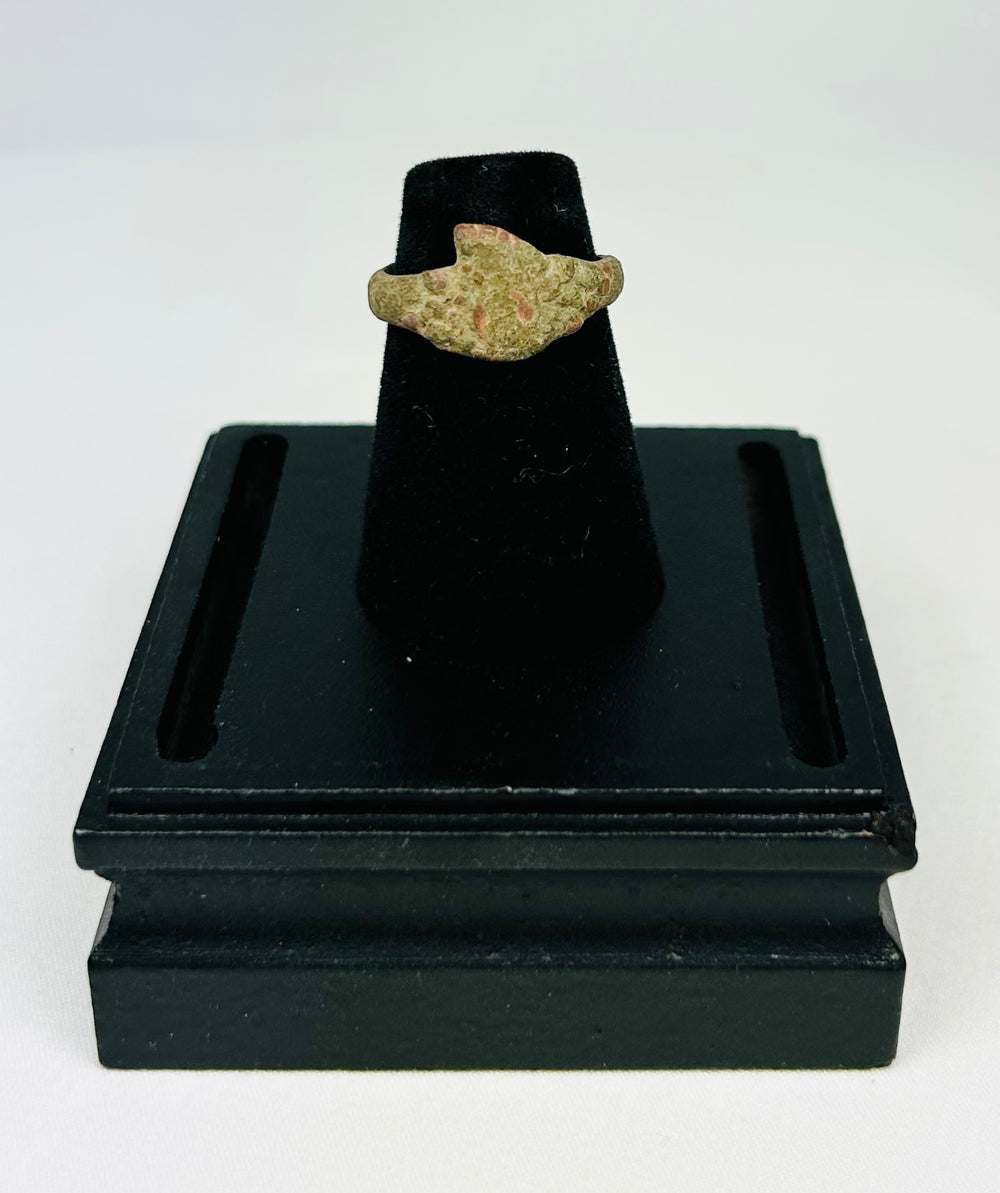 Museum-style photograph of an ancient bronze ring with natural green and brown patina