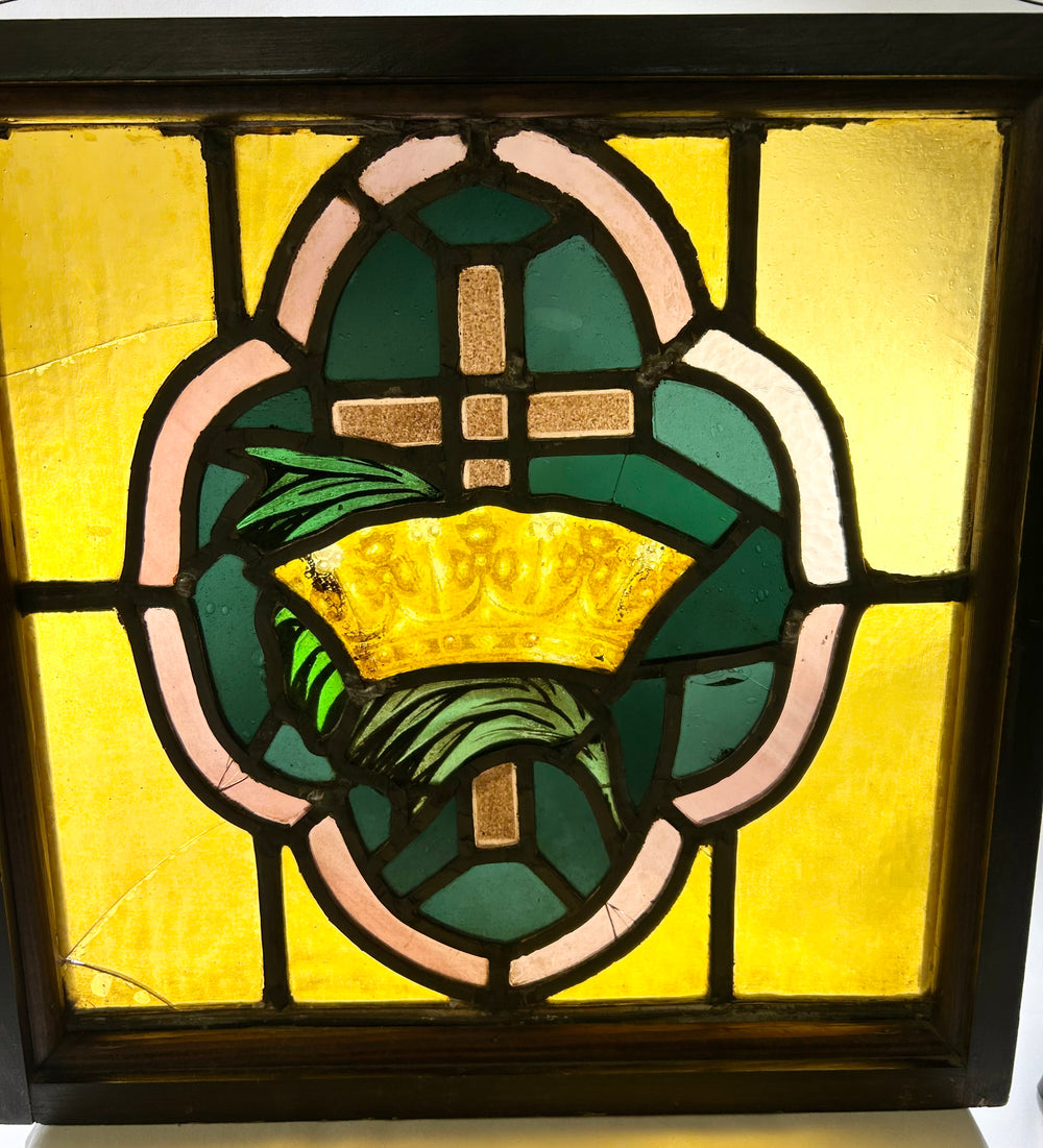 16-inch square stained glass panel, early 20th century, depicting cross and crown motif in colored glass with wooden frame.