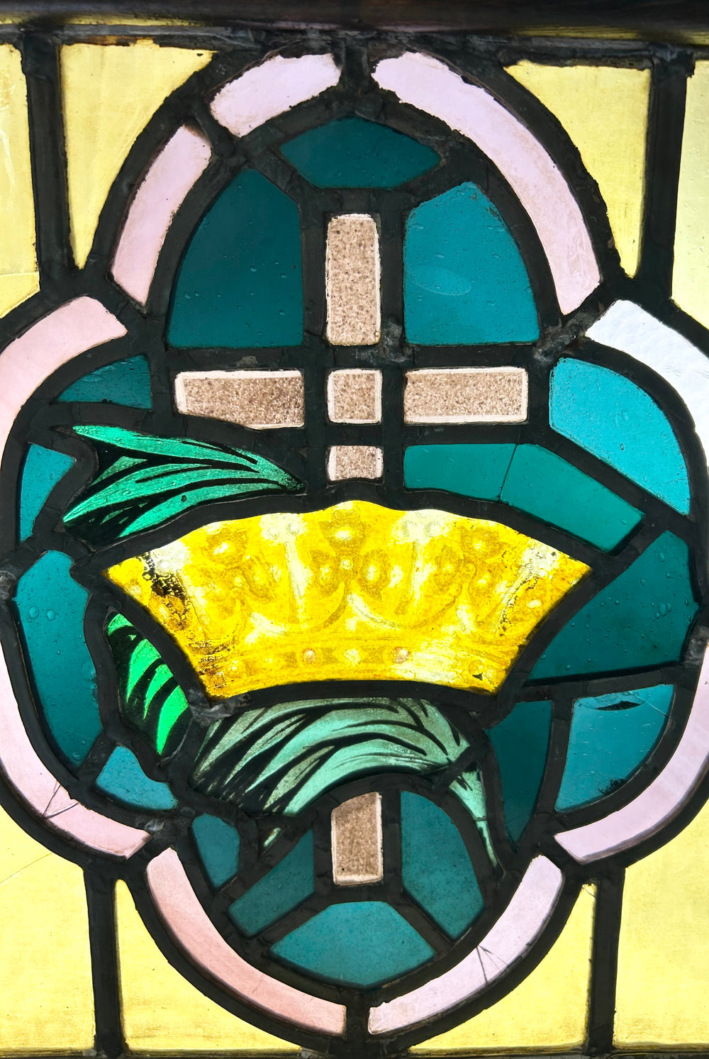 Early 20th-century stained glass artwork, cross and crown design in amber, green, and pink glass, framed in wood, 16x16 in.