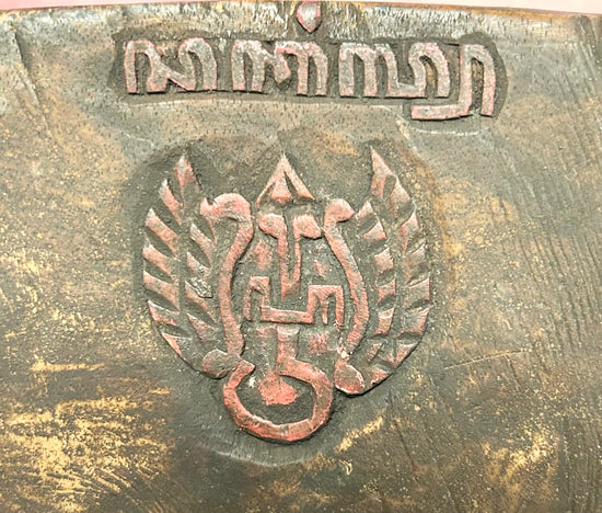 Back view of stamp or carving on a late 19th-century Javanese carved wooden Cakil mask showing interior surface and hanging cord on a black display stand.