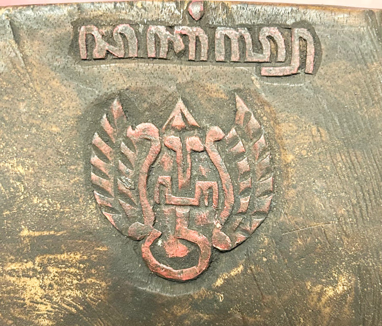 Back view of stamp or carving on a late 19th-century Javanese carved wooden Cakil mask showing interior surface and hanging cord on a black display stand.