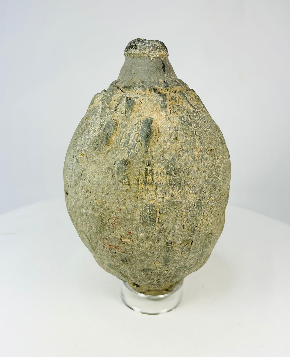 Front view of an Islamic ceramic hand grenade from Greater Persia, 10th–12th century CE, showing its globular form, textured surface, and aged patina.