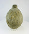 Front view of an Islamic ceramic hand grenade from Greater Persia, 10th–12th century CE, showing its textured surface, conical neck, and aged earthen patina on a white background.
