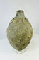 Islamic ceramic hand grenade from Greater Persia, 10th–12th century CE, shown in a straight-on view highlighting its textured globular body, aged patina, and narrow neck on a white background.