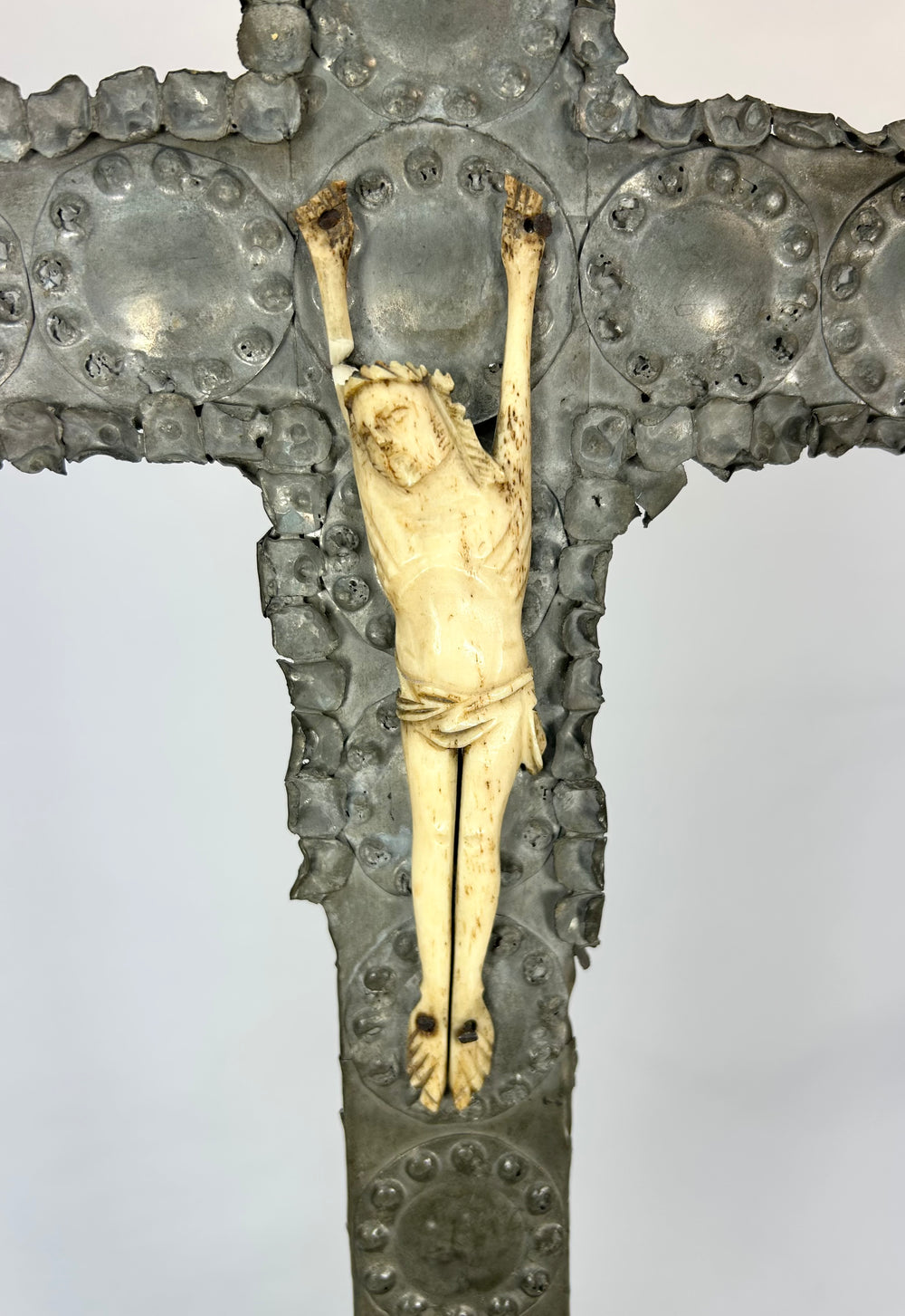Colonial-period Spanish crucifix, wood sheathed in tin repoussé with carved bone Christ, decorative motifs, and signs of historic devotional use.