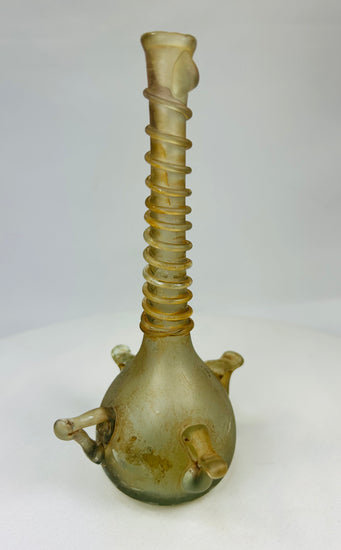 Angled right view of early Islamic glass bottle with long ribbed neck and twin loop handles, pale green tone.