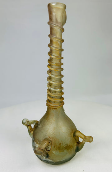 Side profile of ancient Middle Eastern glass vessel with tall neck, rounded base, and slight weathering from age.