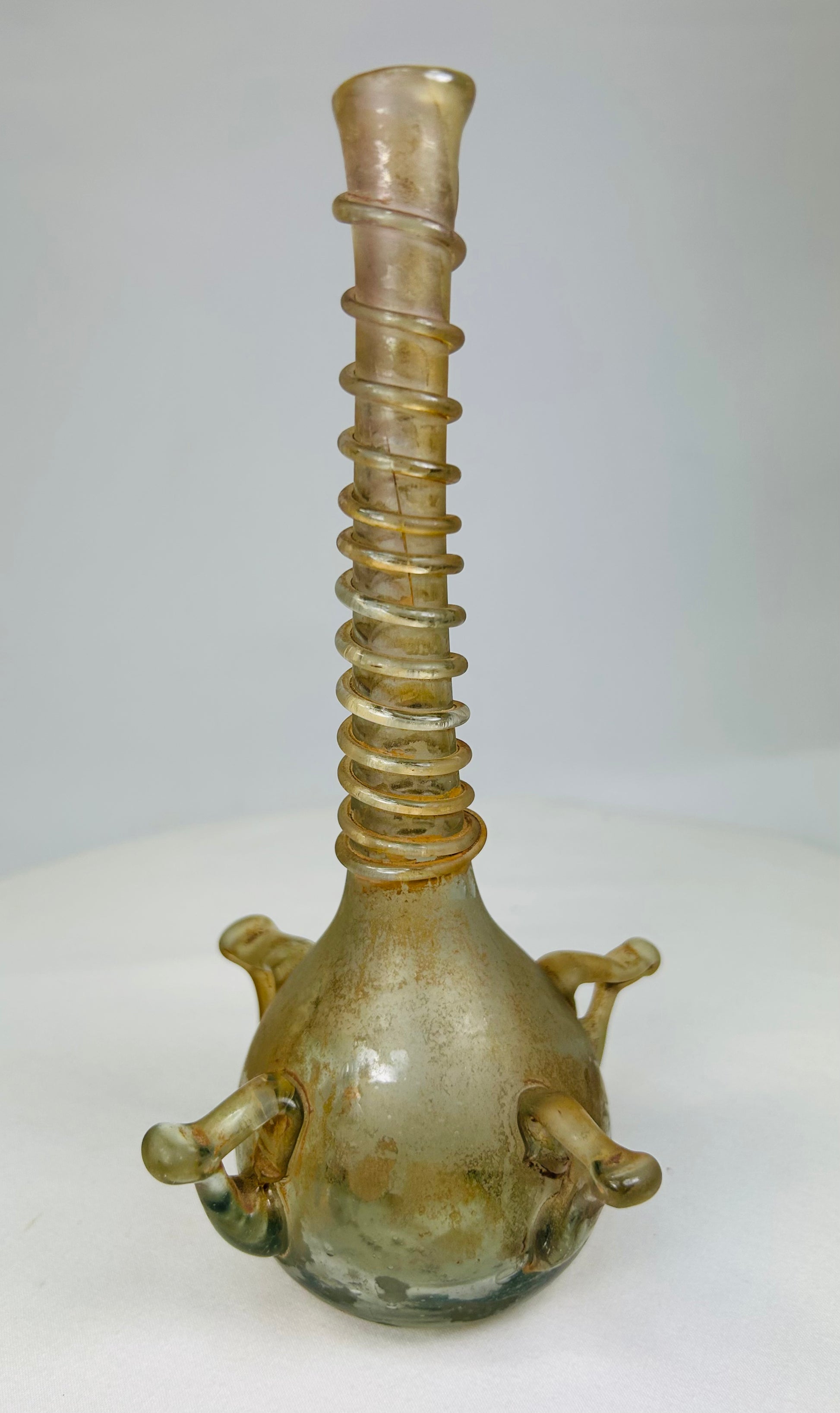 Ancient Islamic glass vessel displayed upright, showcasing translucent body and ribbed neck craftsmanship.