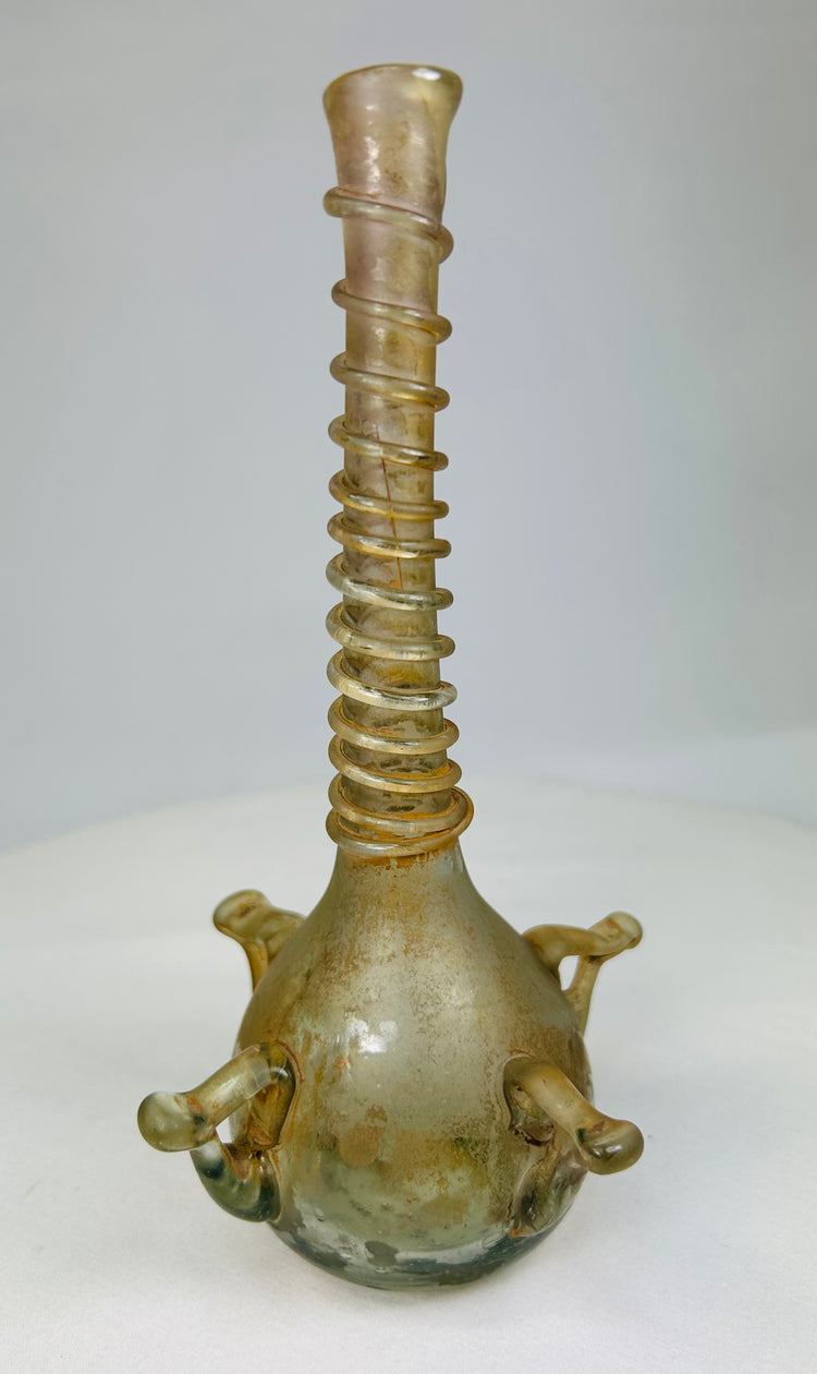 Ancient Islamic glass vessel displayed upright, showcasing translucent body and ribbed neck craftsmanship.