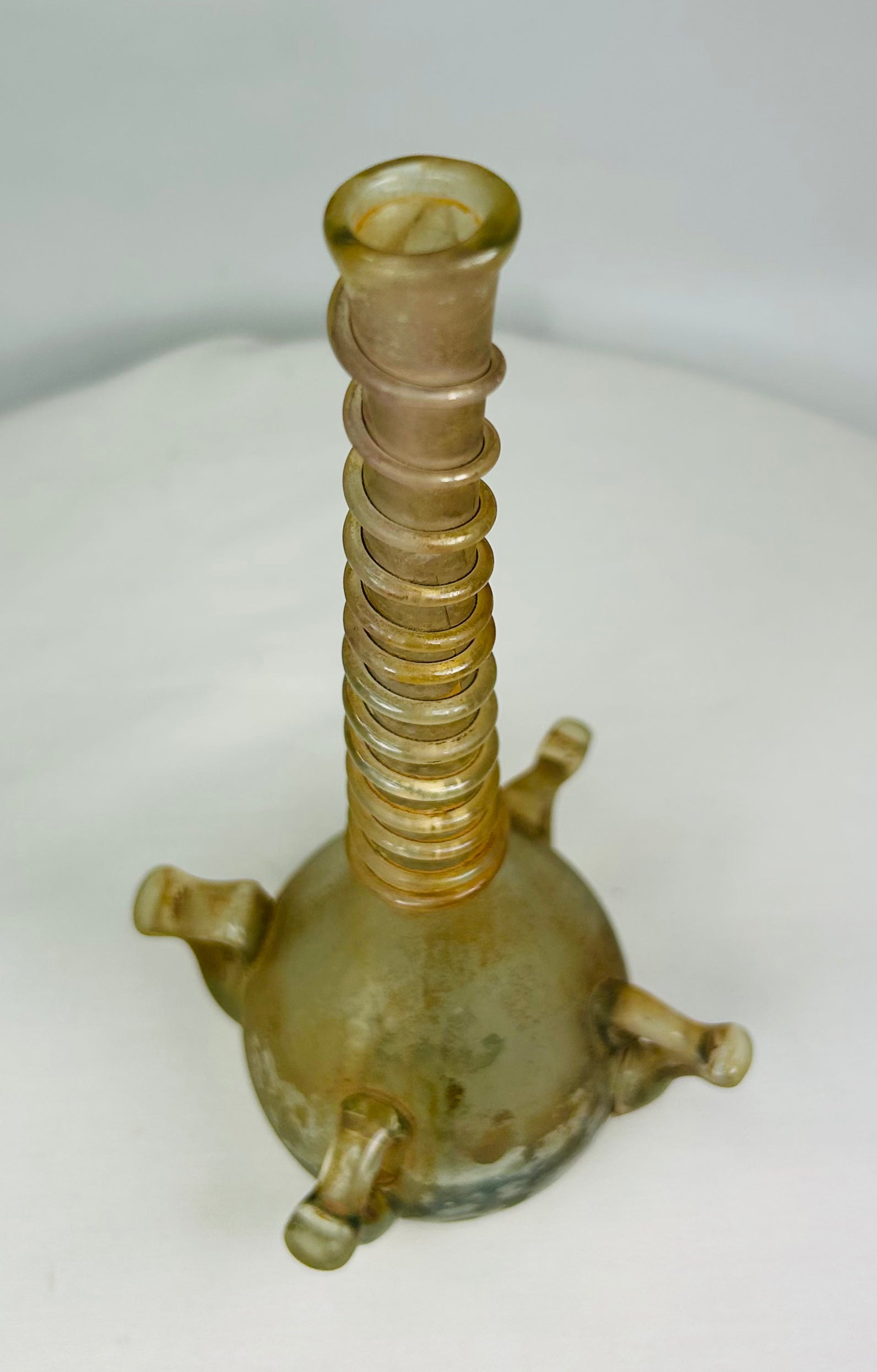 Overhead view showing circular mouth and symmetrical ribbing of ancient Islamic glass bottle.