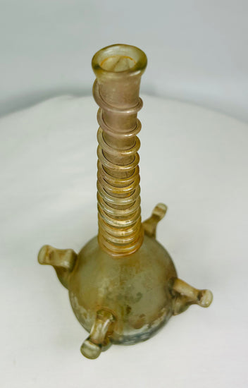 Overhead view showing circular mouth and symmetrical ribbing of ancient Islamic glass bottle.
