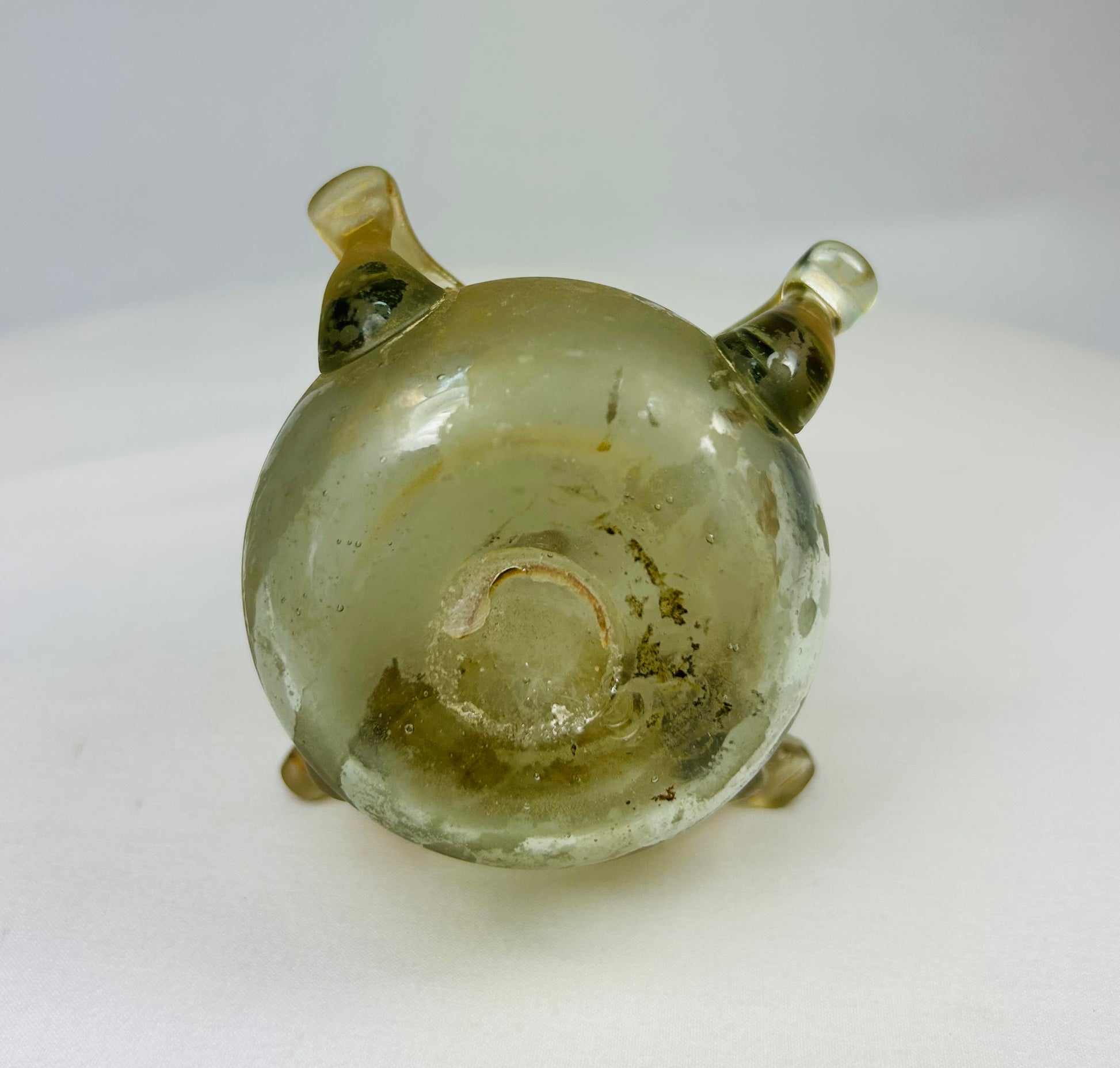 Base of early Islamic glass vessel with stable wear pattern and subtle iridescence from burial patina.