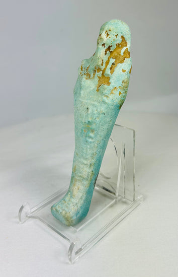 Angled left view of ancient Egyptian turquoise-blue faience ushabti showing mummiform shape and subtle glaze variation.