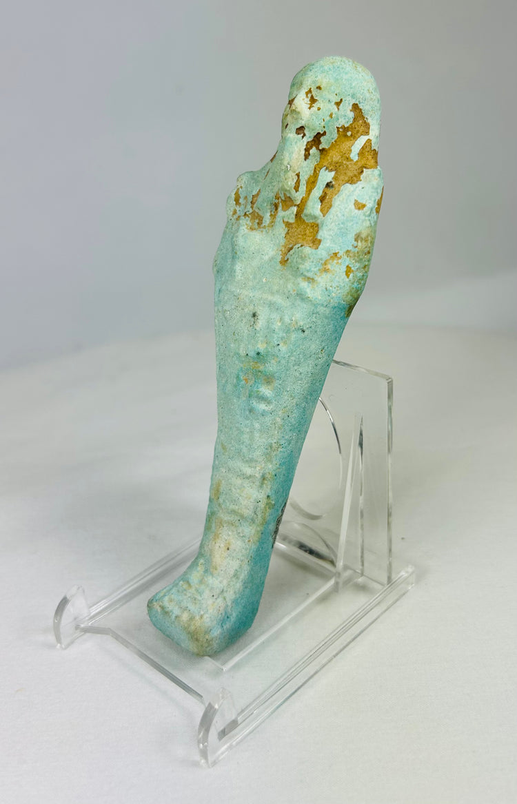 Angled left view of ancient Egyptian turquoise-blue faience ushabti showing mummiform shape and subtle glaze variation.