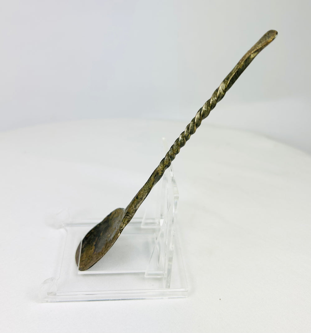 Left side profile of ancient bronze spoon highlighting elegant spiral handle design and encrusted surface texture.