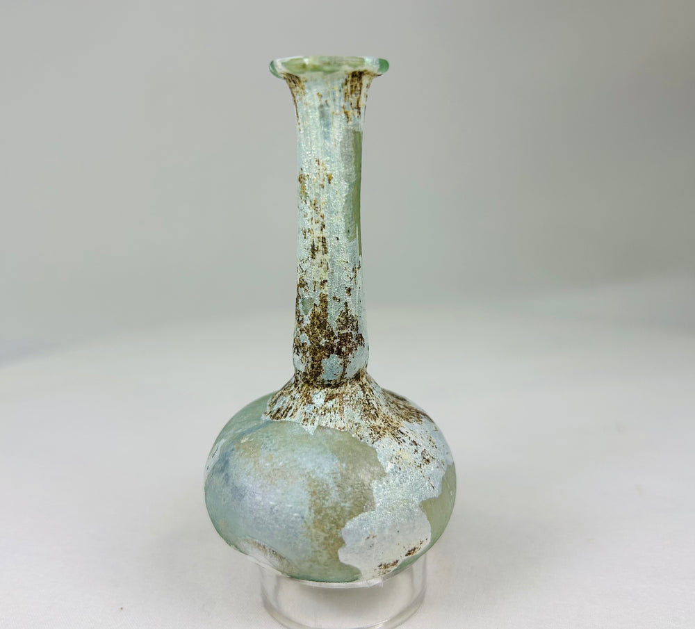 Ancient Roman glass bottle viewed at a soft angle showing natural mineral deposits and patina.