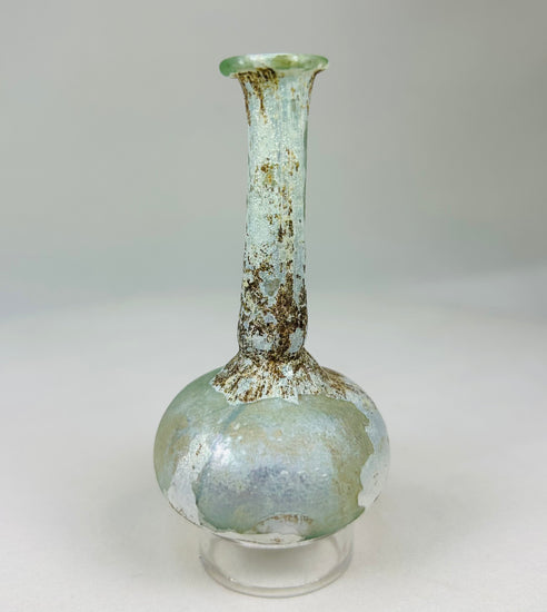 Ancient Roman glass bottle displaying elegant proportions, flared mouth, and iridescent sheen.