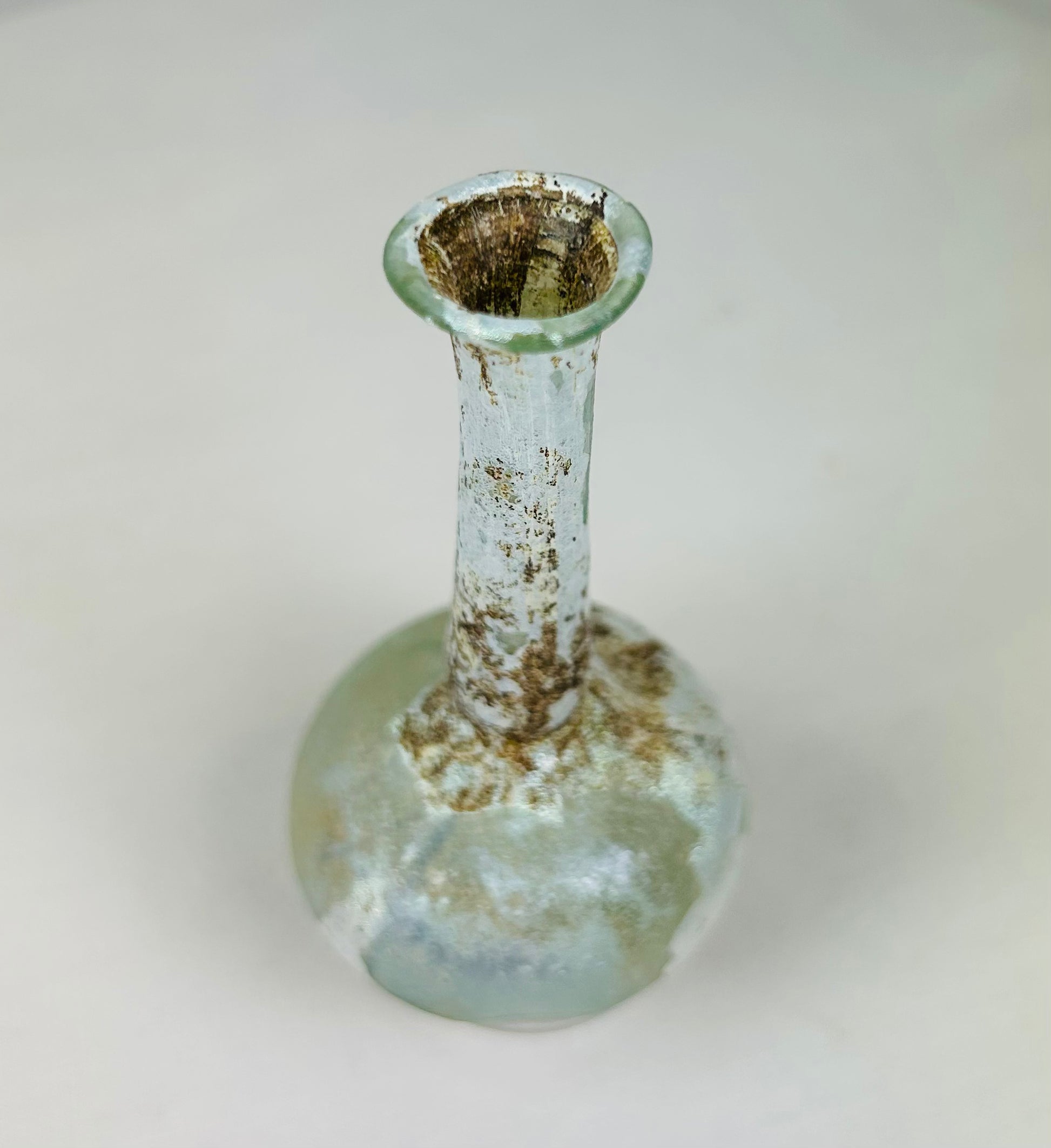 Overhead view of Roman glass bottle revealing narrow mouth, circular opening, and internal residue.
