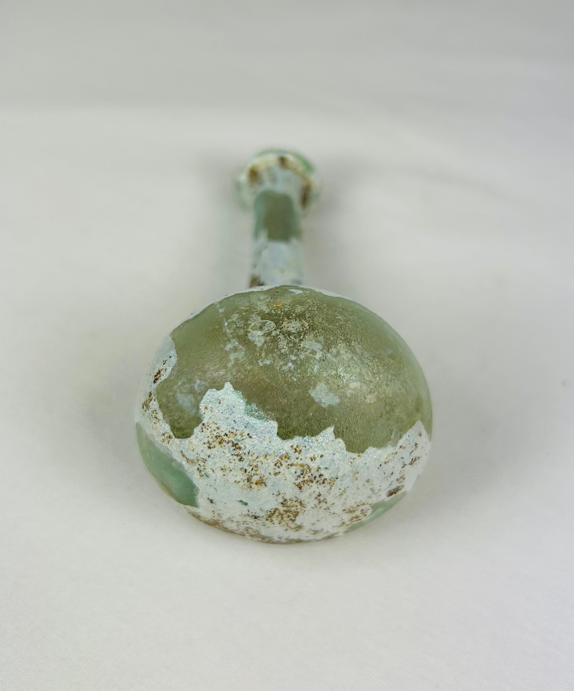 Base of Roman glass bottle with smooth circular finish and aged iridescent surface from antiquity.