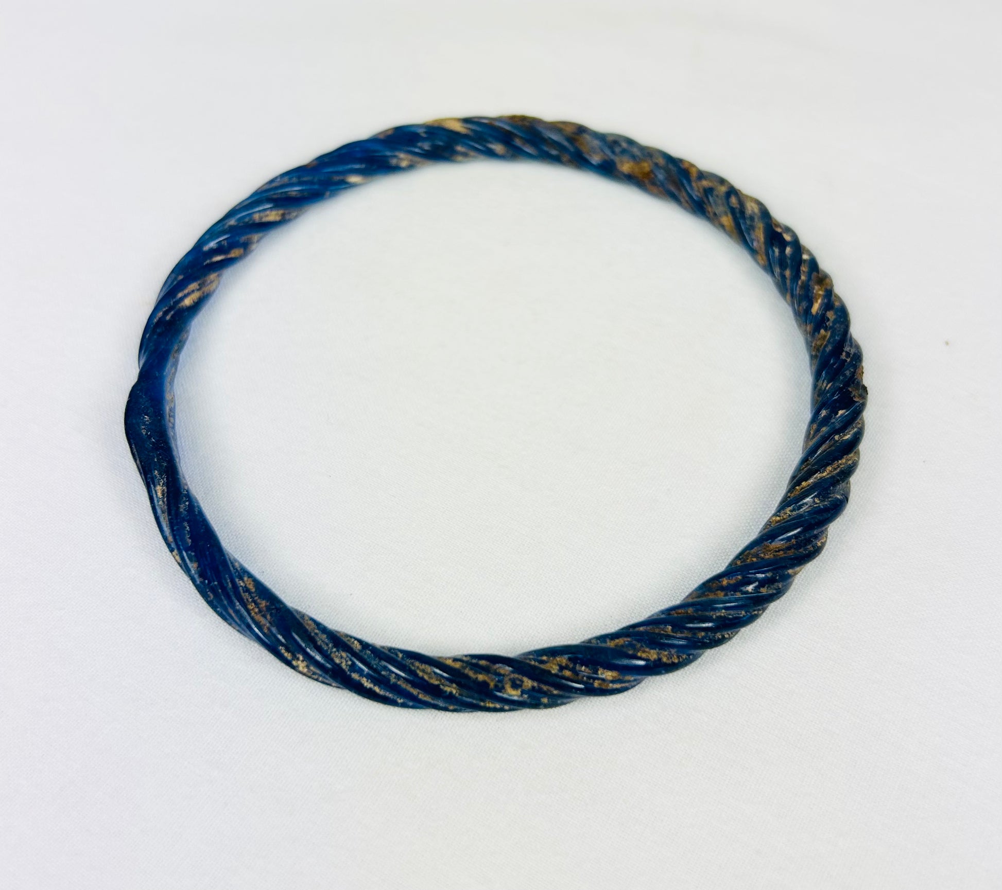 Roman glass bracelet with deep blue color and natural mineral weathering from centuries of burial.