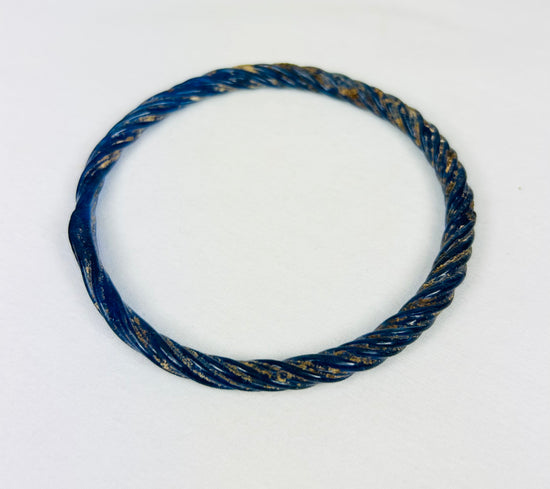 Roman glass bracelet with deep blue color and natural mineral weathering from centuries of burial.