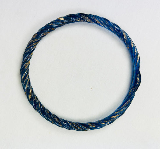 Ancient Roman cobalt-blue glass bracelet reflecting iridescent highlights under light.