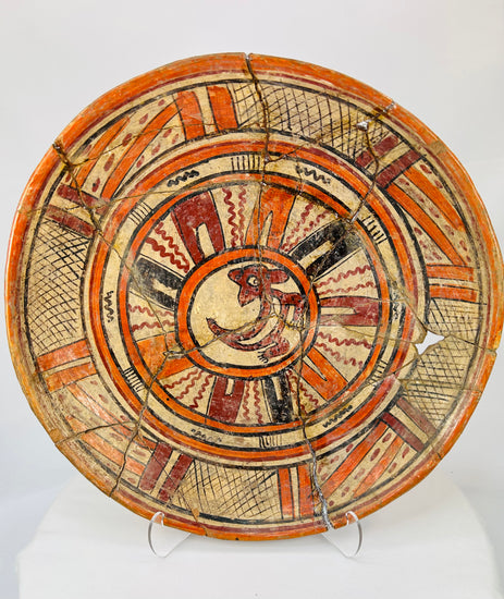Front view of Mesoamerican polychrome earthenware plate showing central stylized animal design and red-black-cream pigment patterning.