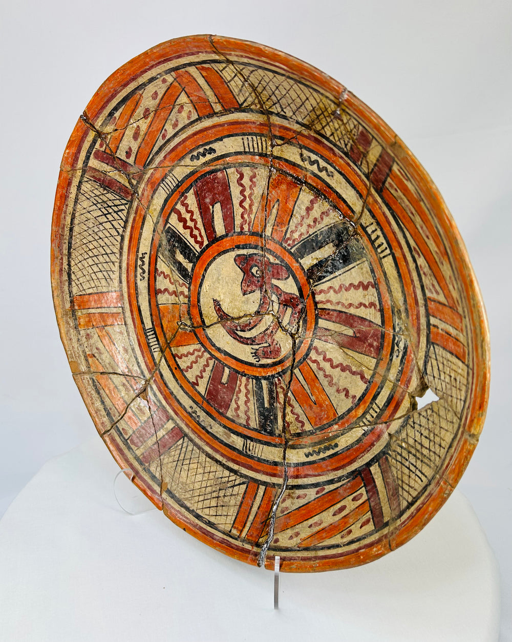 Left-side oblique angle of ancient Mesoamerican polychrome plate showing curvature and painted rim motifs.