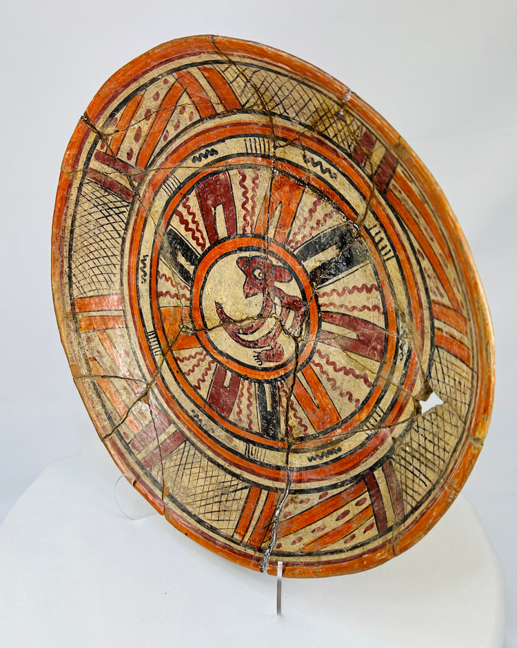 Left-side oblique angle of ancient Mesoamerican polychrome plate showing curvature and painted rim motifs.