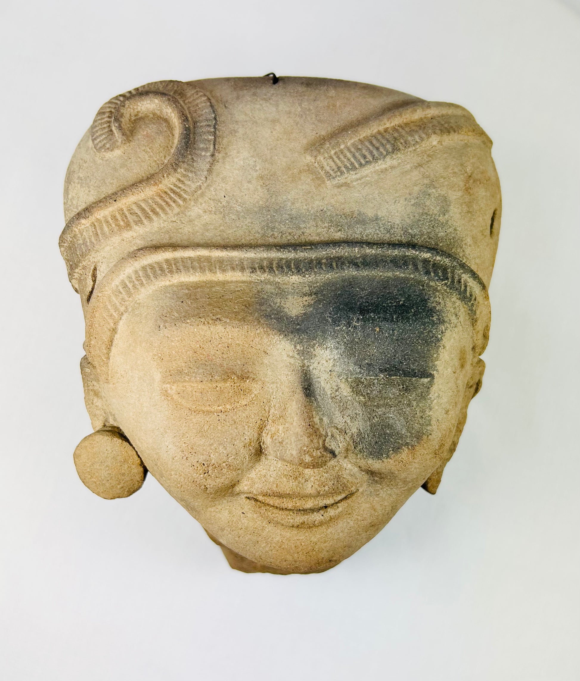 Overhead view of Pre-Columbian terracotta head revealing finely modeled coiffure and crown.