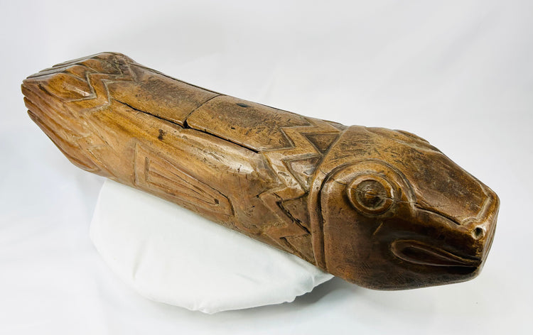 Angled front perspective of antique wooden fish drum highlighting carved head and mouth detail