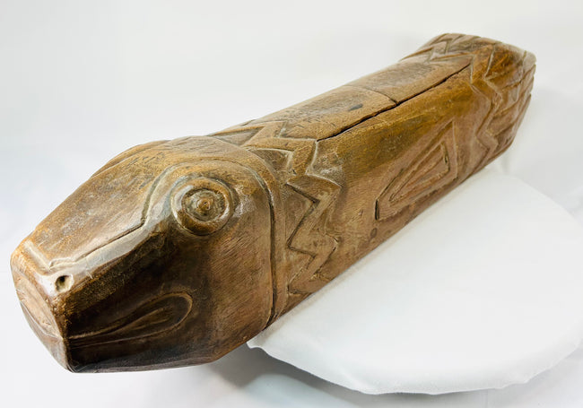 Close-up of antique wooden fish drum highlighting carved eye and mouth details with visible patina.