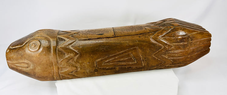 Full side profile of hand-carved wooden fish drum displaying zigzag and geometric motifs.