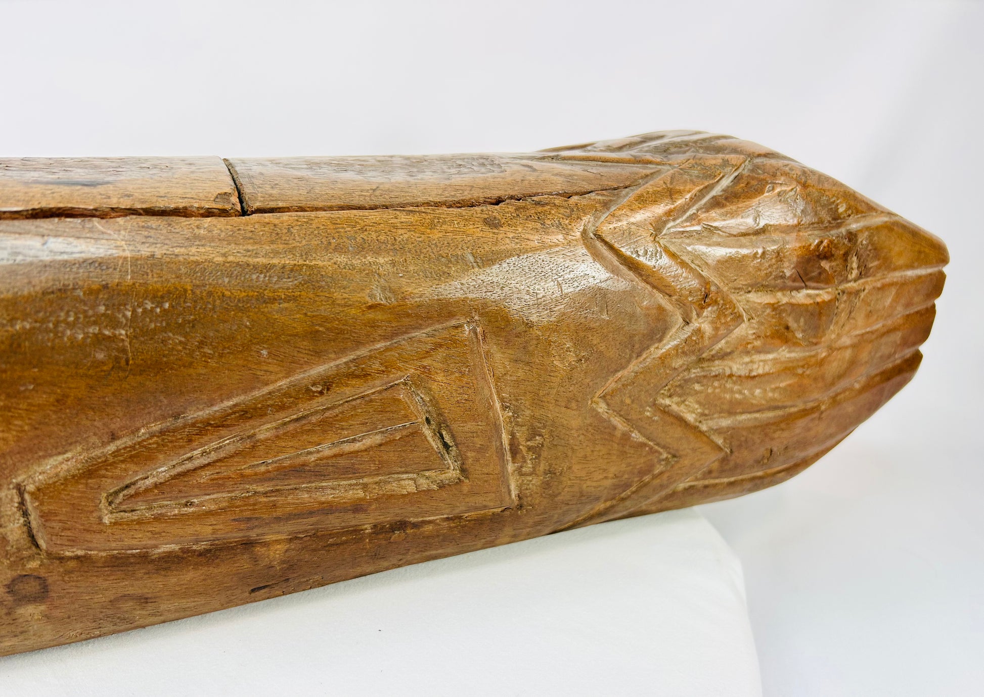 Rear section detail of carved wooden fish drum with zigzag tribal motifs and deep patina.