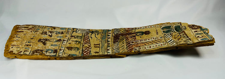 Side angle view of Egyptian coffin fragment revealing curved wooden surface and remaining pigment layer