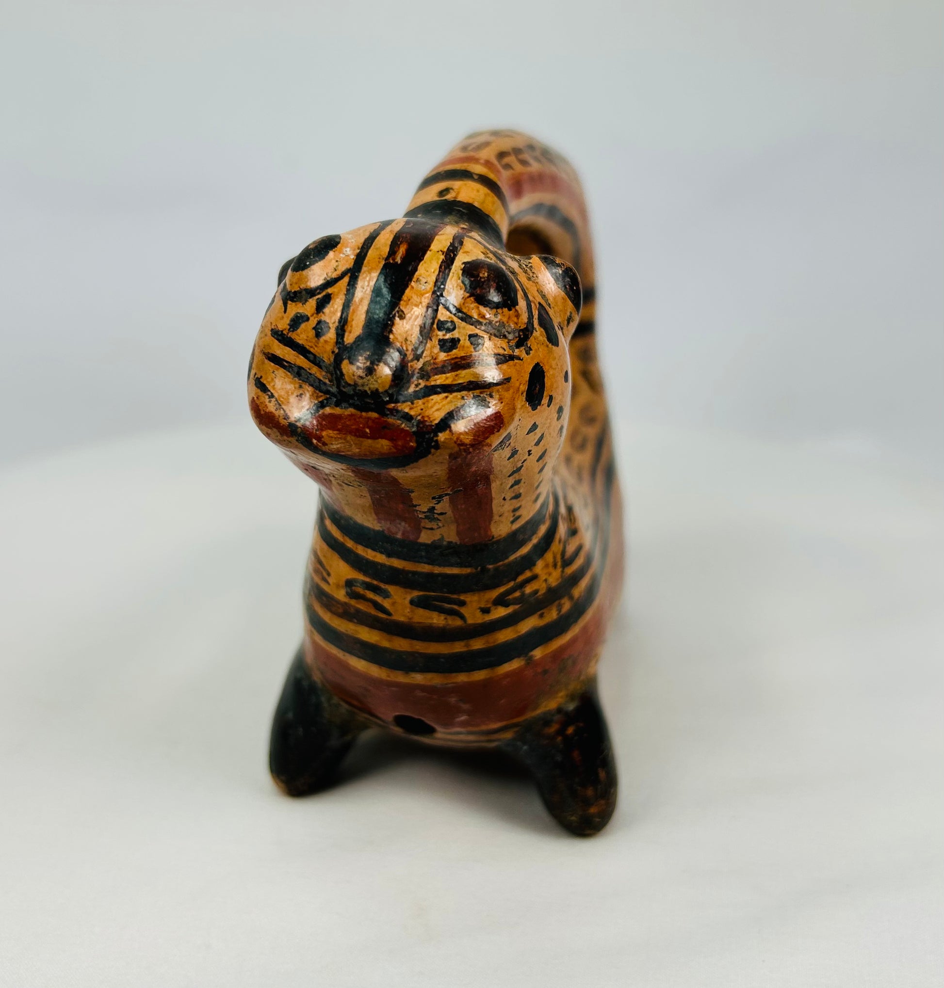 Front-facing view of feline effigy rattle bowl showing painted geometric and spotted motifs, Nicoya style